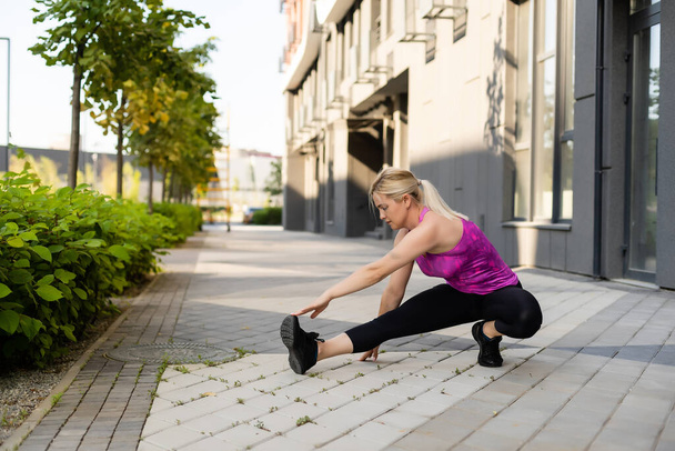 Fitness-Sportlerin in modischer Sportbekleidung, die Yoga-Fitness-Übungen auf der Straße macht, Outdoor-Sport, urbaner Stil - Foto, Bild