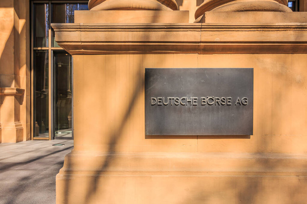 Колонны у входа с коричневым фасадом здания Германской фондовой биржи. Дом в солнечном сиянии с металлическими вставками и подсветкой. Стеклянные двери на заднем плане - Фото, изображение