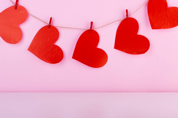 red hearts on a rope on a pink background. background for the valentine's day holiday - Fotografie, Obrázek
