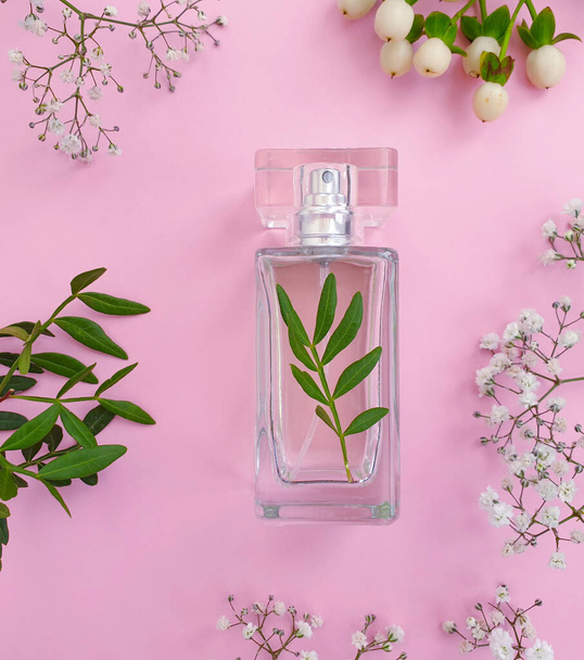 fles parfum bloem op een gekleurde achtergrond - Foto, afbeelding