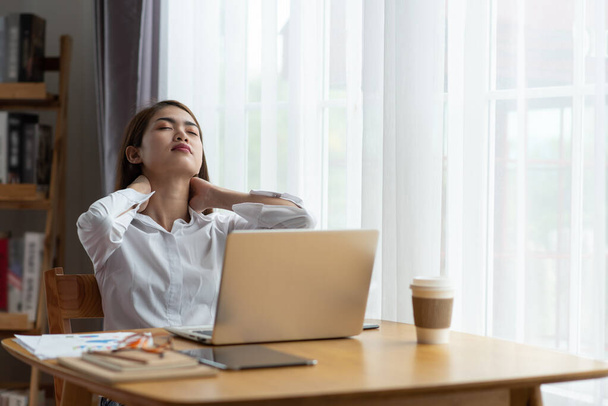 Молодая азиатская деловая женщина с болью в шее в офисе - Фото, изображение