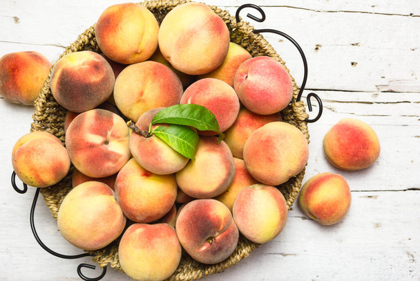 Зрізати червоні персики в кошику на сільському білому столі, вид зверху. Здорові органічні фрукти
. - Фото, зображення