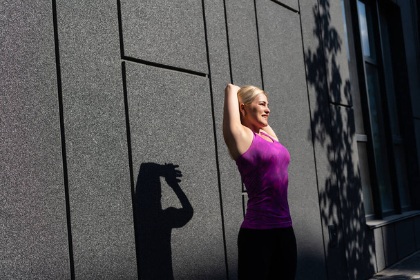 Fitness femme sportive dans la mode vêtements de sport faire du yoga exercice de fitness dans la rue, sports de plein air, style urbain - Photo, image