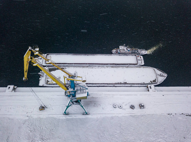 Snow-covered barges in the industrial port. Snowy day, blizzard. Aerial drone view. - Photo, Image