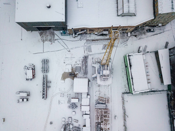 Una grúa en un astillero cubierto de nieve. Día nevado, ventisca. Vista aérea del dron. - Foto, Imagen