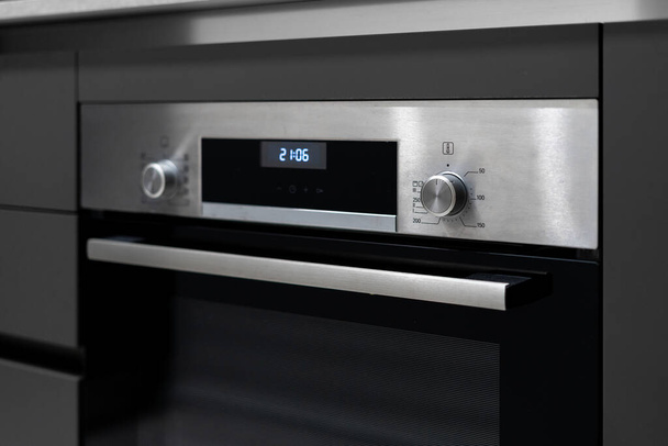 Selective focus on built in oven appliance with time settings on display and buttons at control panel. Modern kitchen in contemporary apartment - Fotografie, Obrázek