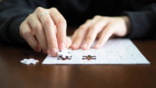 hand pick a piece of jigsaw to connect success on wooden table top selected focus - Foto, Imagem