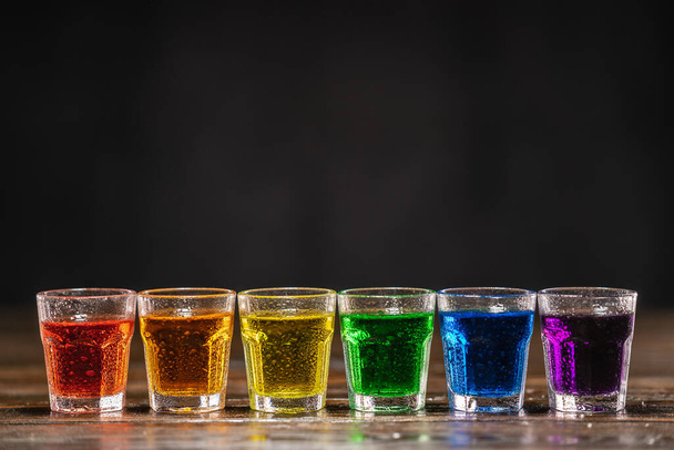 Постріли з різнокольоровим алкоголем, стоячи в ряд
 - Фото, зображення