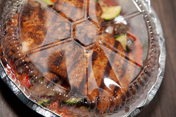 Grillezett csirkemell, paradicsom és grillezett brokkoli, gomba és cukkini elvitelre szolgáló edényben - Fotó, kép