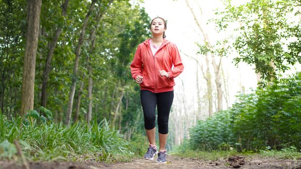 aziatische vrouw running in bos dragen jas - Foto, afbeelding