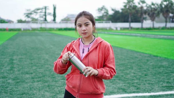 asiático corredor mujer beber agua en stadion - Foto, imagen