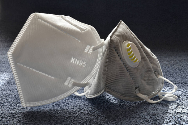 Maschera KN95 o N95 con e senza valvola di protezione pm 2.5 e virus corona su sfondo nero. Prevenzione della diffusione del virus e della pandemia COVID-19. - Foto, immagini