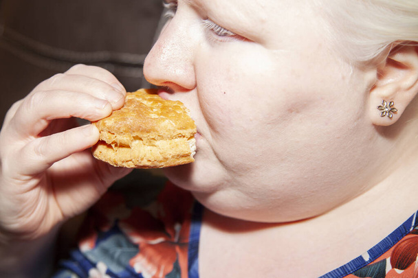 Κοντινό πλάνο μιας γυναίκας αλμπίνο που τρώει ένα μπισκότο βουτυρόγαλα - Φωτογραφία, εικόνα