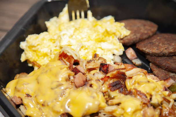 卵、朝食ソーセージ、黒テイクアウトコンテナ内のチージーハッシュブラウン - 写真・画像