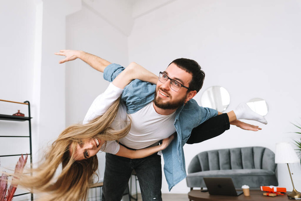 Young happy cheerful couple having fun in living room at home. High quality photo - Foto, imagen