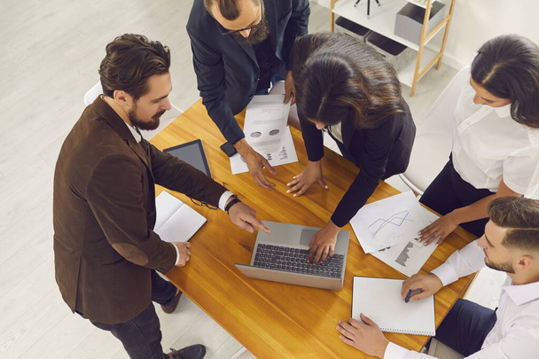 Grupo de pessoas de negócios companheiros de equipe em pé em torno de laptop e discutindo startup ou apresentação de marketing - Foto, Imagem