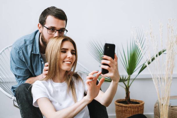 Jovem casal alegre usando telefone celular, fazendo selfie no smartphone juntos. Foto de alta qualidade - Foto, Imagem