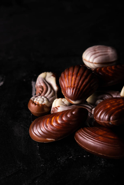 Belgian chocolate seashells on a black table - Fotografie, Obrázek
