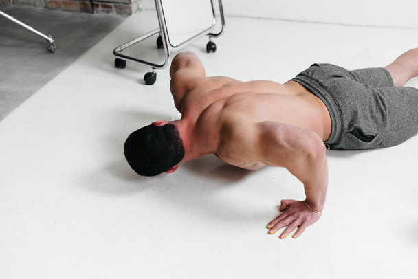 A young athlete does push-ups in the studio. - Photo, image