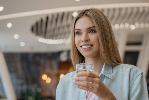 Schöne lächelnde Frau mit einem Glas mit frischem Wasser. Ernährung, Gewichtsverlust, gesunder Lebensstil  - Foto, Bild