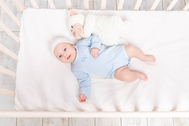 bebé en cuna con juguete de oso de peluche se acuesta o se despierta por la mañana, la familia y el concepto de nacimiento - Foto, Imagen
