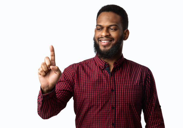 Μαύρος τύπος κρατώντας αόρατο αντικείμενο στο δάχτυλο πάνω από το λευκό φόντο - Φωτογραφία, εικόνα
