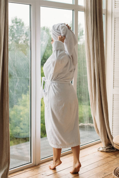 young girl in a bathrobe and turban in the spa at the big window - Fotoğraf, Görsel