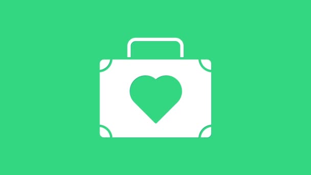 Valkoinen matkalaukku matkustaa sydän kuvake eristetty vihreällä taustalla. Kuherruskuukauden symboli. Matkalaukkukyltti. Matkatavaroiden kuvake. 4K Video motion graafinen animaatio - Materiaali, video