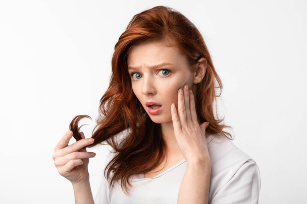Red-Haired Girl Touching Hair Having Split Ends Problem, White Background - Foto, Imagem