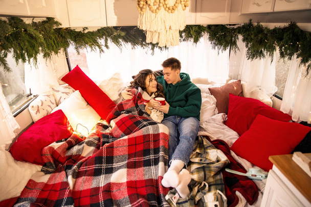 クリスマスの装飾が施されたベッドで楽しくリラックスした若い美しいカップル - 写真・画像