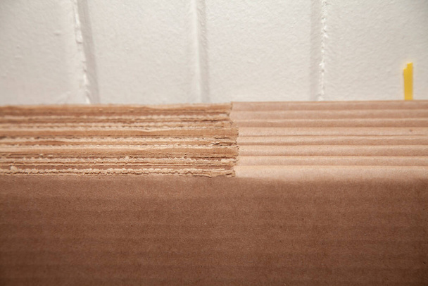 Siete cajas de cartón sin usar y aplanadas contra una pared blanquecina - Foto, imagen