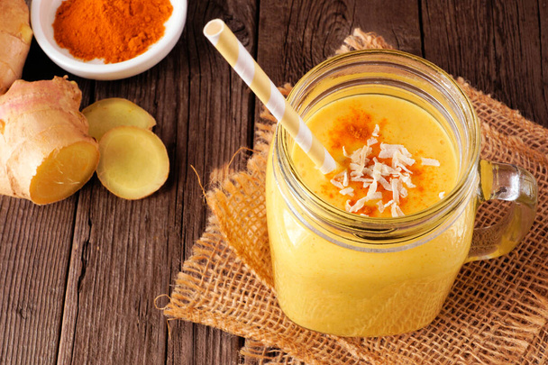 Pineapple, turmeric, ginger smoothie in a mason jar. Above view with a dark wood background. Healthy immune boosting, weight loss, anti-inflammatory. - Photo, Image