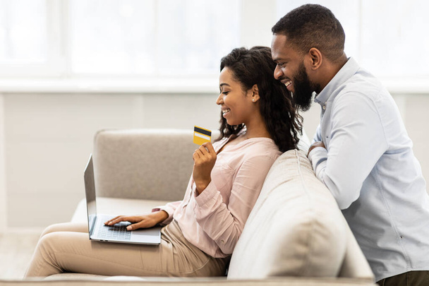 Black couple using computer and debit credit card at home - Photo, Image
