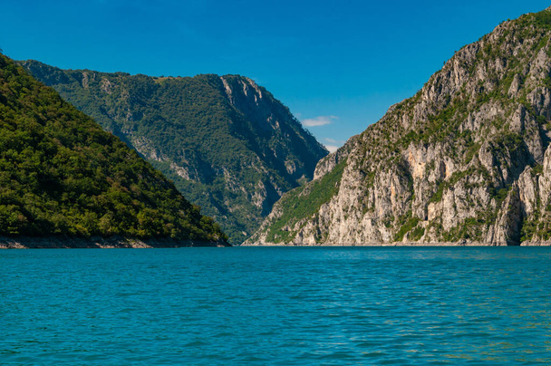 Чорногорія. Вид на озеро Піва, розташоване між горами. Озеро є штучним водосховищем прісної води. Яскраве блакитне небо. - Фото, зображення