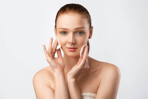 Ginger-Haired Girl Cleansing Skin With Cotton Pads Over White Background - Foto, Imagem