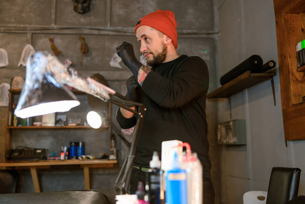 Profesyonel Sakallı Kafkas dövme ustası rahat atmosferik stüdyoda çalışıyor. - Fotoğraf, Görsel