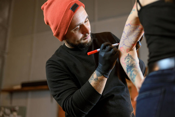 Profesional hombre barbudo caucásico tatuaje maestro está trabajando en acogedor estudio atmosférico - Foto, imagen