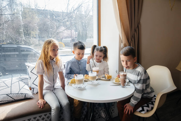 Una gran compañía amistosa de niños celebra la fiesta en un café con un delicioso postre. El día del nacimiento - Foto, Imagen