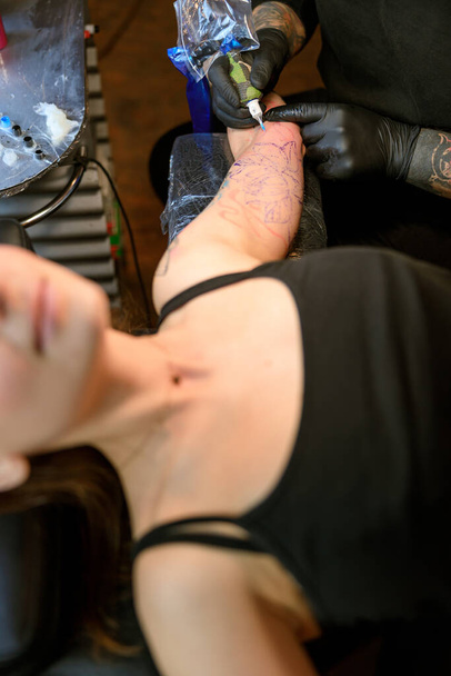 Profesional hombre barbudo caucásico tatuaje maestro está trabajando en acogedor estudio atmosférico - Foto, imagen