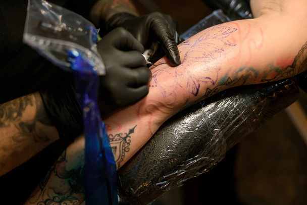 Профессиональный мастер татуировки с бородой работает в уютной атмосфере студии - Фото, изображение