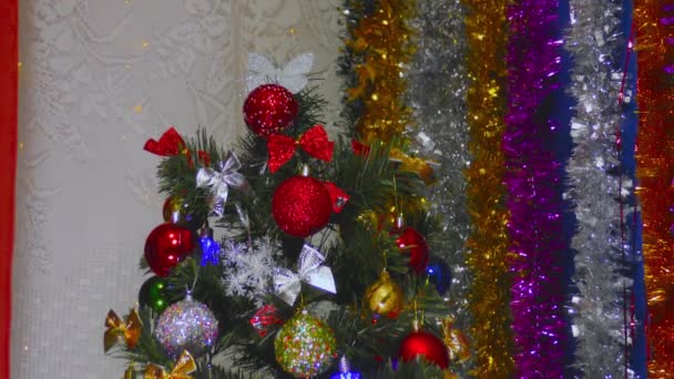 Karácsonyfa díszített különböző és színes játékok a háttérben az újévi dekorációk - Felvétel, videó