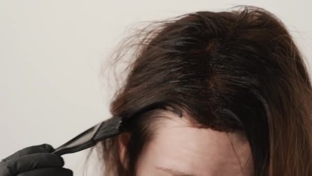 Woman coloring gray hair roots using a brush. Hair dyeing tips at home - Footage, Video