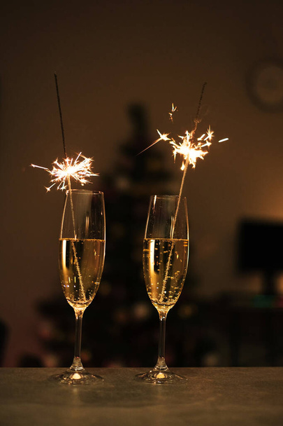 copos de champanhe, brilhos no fundo de uma árvore de Natal e guirlandas. Boas festas. Feliz Natal e Feliz Ano Novo - Foto, Imagem