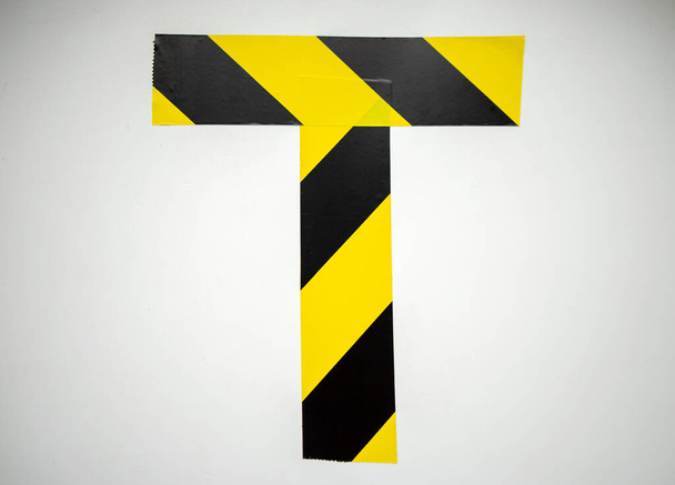 T harfi, yasaklayıcı siyah ve sarı renkli yapışkan banttan yapılmıştır. - Fotoğraf, Görsel