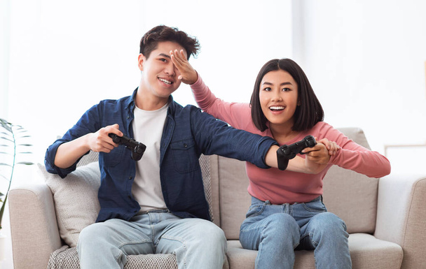 alegre asiático cónyuges tener divertido jugando video juego sentado en interior - Foto, Imagen