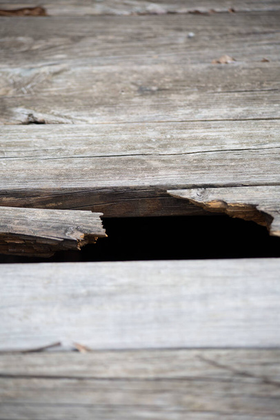 Κοντινό πλάνο μιας τρύπας στις ξύλινες σανίδες ενός υπαίθριου διαδρόμου - Φωτογραφία, εικόνα