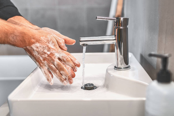 Washing hands with soap and warm water for 20 seconds for corona virus COVID-10 prevention. Work man for corona virus hygiene to stop spreading coronavirus - Φωτογραφία, εικόνα
