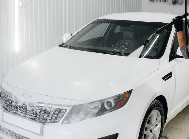 Modern washing with foam and high-pressure water of a white car. Car wash - Foto, imagen