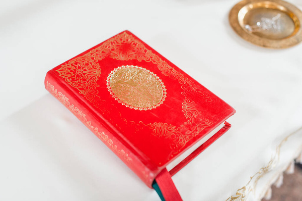 Biblia santa cubierta dura roja en el mantel blanco. Enfoque selectivo - Foto, Imagen