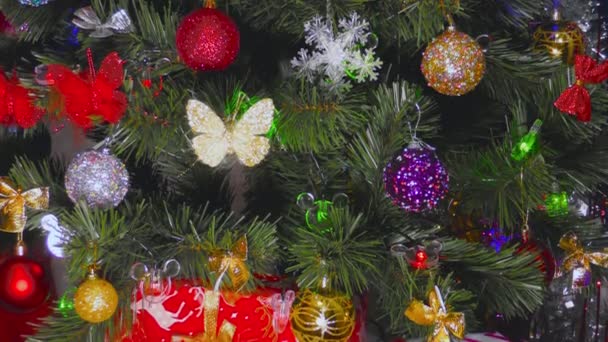 Vor dem Hintergrund des Neujahrsschmucks schmückt ein Weihnachtsbaum mit verschiedenen und bunten Spielzeugen - Filmmaterial, Video